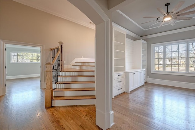 staircase with ornamental molding, ceiling fan, and wood finished floors