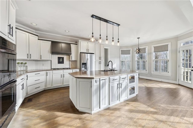 kitchen with white cabinetry, sink, hanging light fixtures, a kitchen island with sink, and stainless steel fridge with ice dispenser