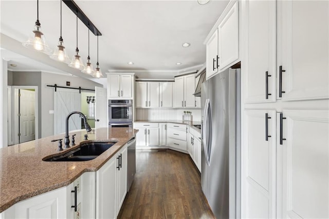 kitchen with sink, white cabinetry, appliances with stainless steel finishes, dark stone counters, and a barn door