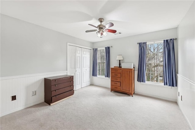 unfurnished bedroom with light colored carpet, ceiling fan, and a closet