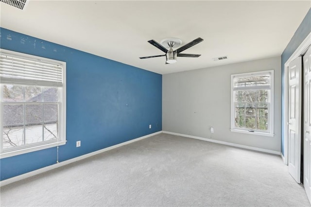 carpeted spare room featuring plenty of natural light and ceiling fan