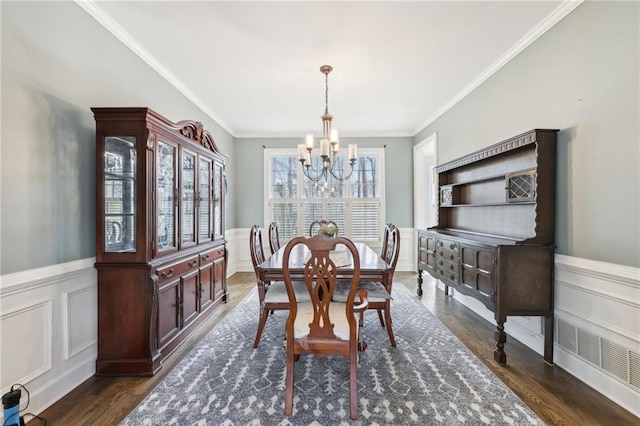 dining space with dark wood-type flooring, ornamental molding, and a notable chandelier