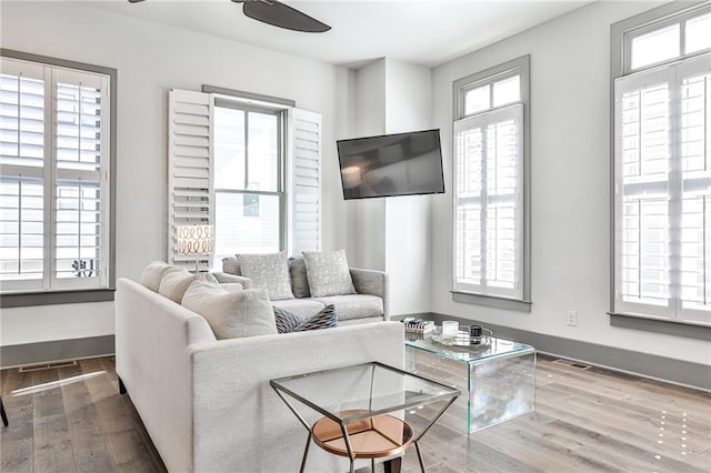 living room featuring ceiling fan, baseboards, and wood finished floors