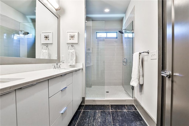 bathroom with a stall shower, double vanity, a sink, and tile patterned floors