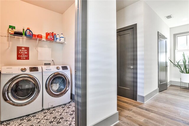 laundry area with laundry area, visible vents, baseboards, wood finished floors, and washing machine and dryer