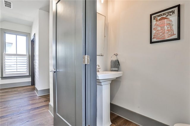 bathroom with lofted ceiling, visible vents, baseboards, and wood finished floors