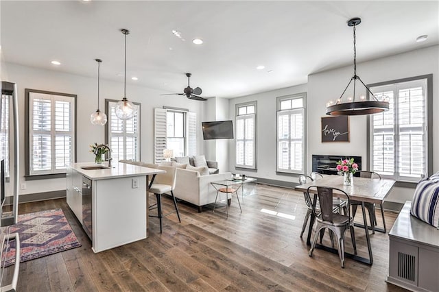 kitchen featuring dark wood finished floors, light countertops, open floor plan, a sink, and plenty of natural light