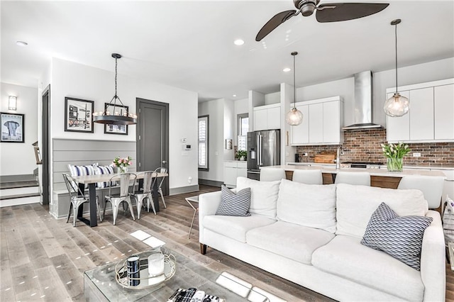 living room with recessed lighting, a ceiling fan, light wood-type flooring, baseboards, and stairs