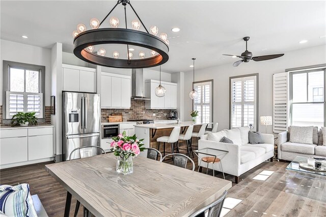 dining area featuring ceiling fan with notable chandelier, dark wood finished floors, and recessed lighting