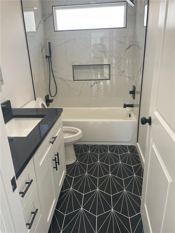 full bathroom featuring tile patterned floors, vanity, a healthy amount of sunlight, and tiled shower / bath combo