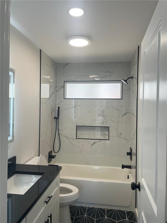 full bathroom featuring tile patterned floors, vanity, toilet, and tiled shower / bath combo