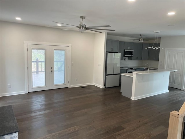 kitchen with dark wood-type flooring, french doors, stainless steel appliances, and a center island with sink