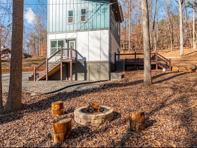 back of property with a fire pit, central AC unit, and a deck