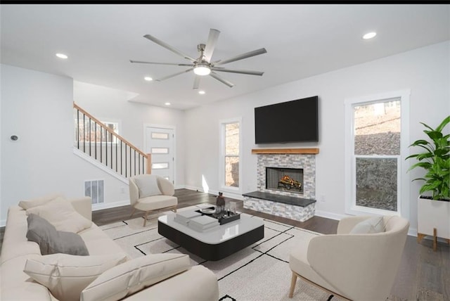 living room featuring a stone fireplace, ceiling fan, plenty of natural light, and light hardwood / wood-style floors