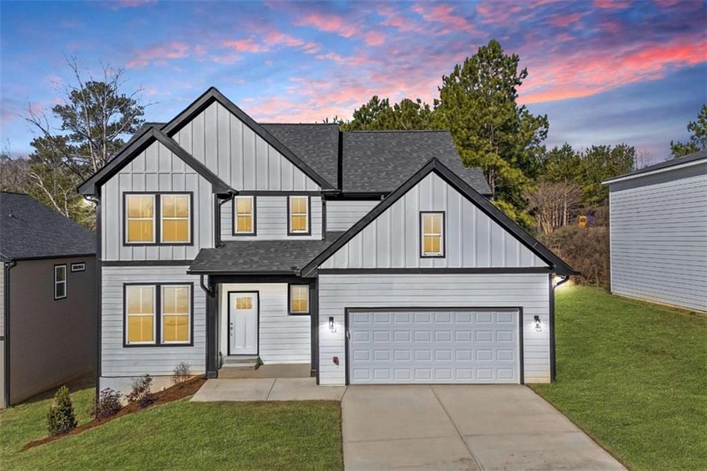 modern inspired farmhouse featuring driveway, a front yard, roof with shingles, board and batten siding, and a garage
