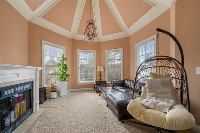 living area with a chandelier, high vaulted ceiling, light colored carpet, baseboards, and a tiled fireplace