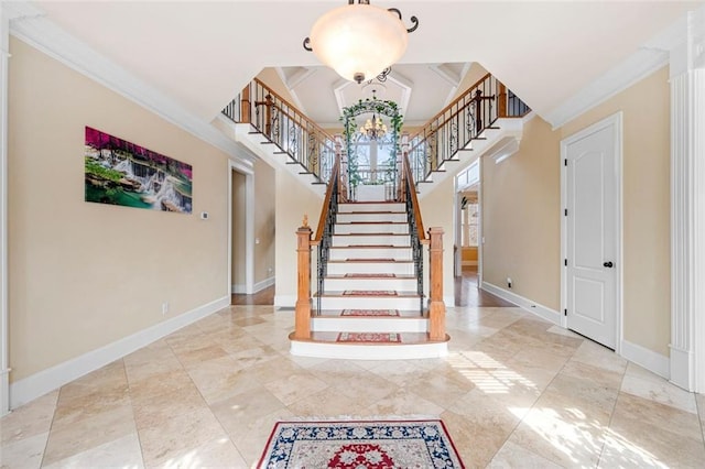 stairs featuring a towering ceiling, baseboards, a chandelier, and crown molding