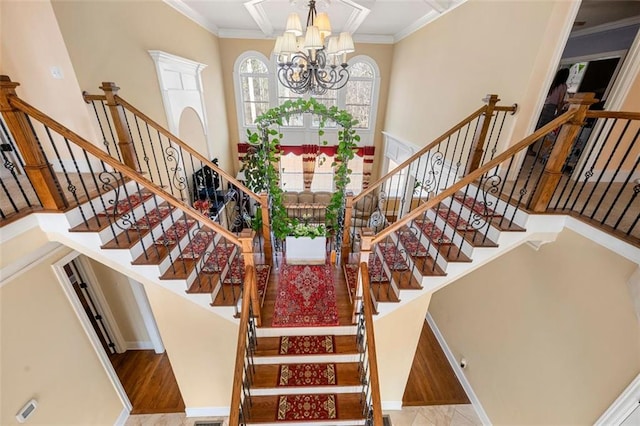 stairway featuring a high ceiling, an inviting chandelier, and crown molding