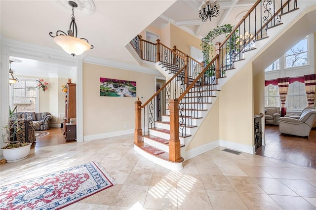 entryway with a healthy amount of sunlight, crown molding, a towering ceiling, and baseboards