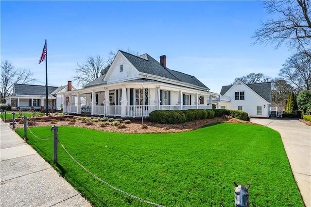 view of front of house featuring a porch, a chimney, and a front lawn