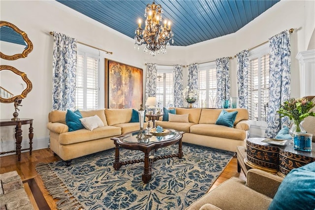 living room with plenty of natural light, wood finished floors, a chandelier, and ornamental molding