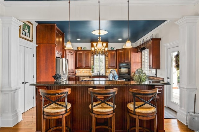 kitchen featuring ornate columns, light wood-style floors, and freestanding refrigerator