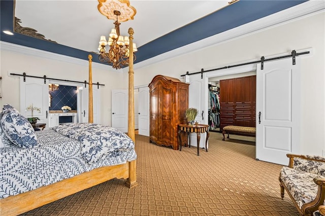 bedroom featuring a walk in closet, ornamental molding, a barn door, a closet, and an inviting chandelier