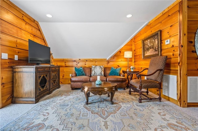 carpeted living area with lofted ceiling, wooden walls, recessed lighting, and visible vents