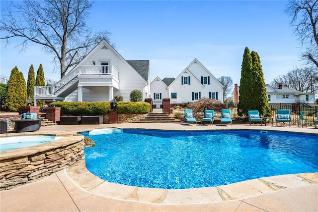 view of swimming pool featuring a fenced in pool, fence, stairs, a patio area, and an in ground hot tub