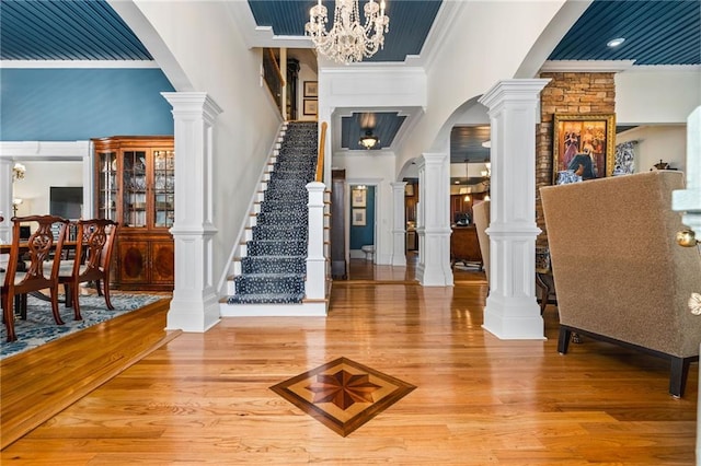 foyer entrance featuring stairway, a notable chandelier, light wood-style floors, and ornamental molding