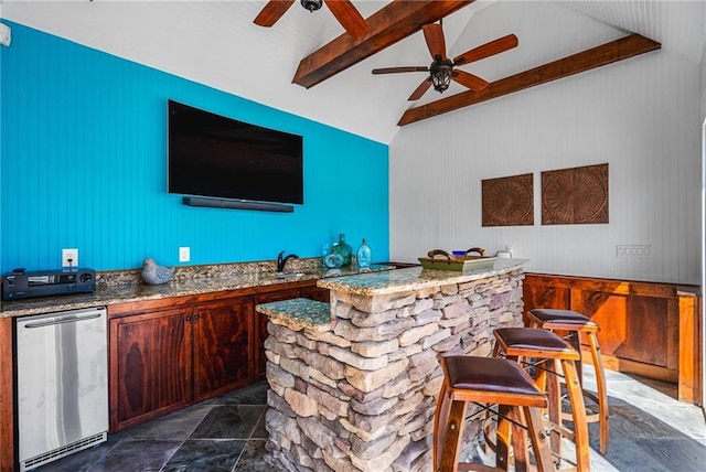 bar featuring a ceiling fan, lofted ceiling with beams, a sink, stone finish flooring, and fridge