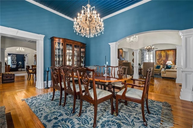 dining area with a notable chandelier, wood finished floors, arched walkways, and decorative columns