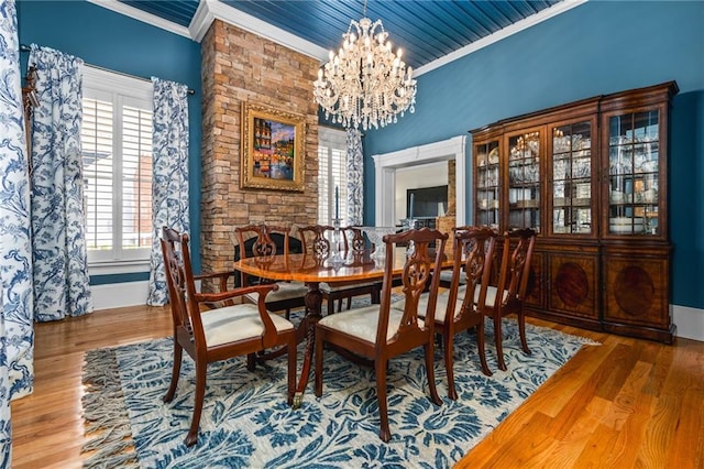 dining space with baseboards, wood finished floors, an inviting chandelier, and ornamental molding