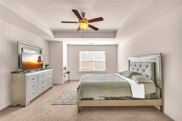 carpeted bedroom featuring ceiling fan and a raised ceiling