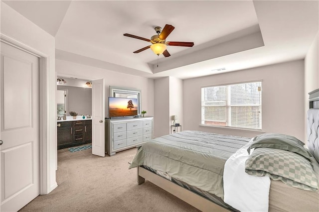 carpeted bedroom featuring ceiling fan, connected bathroom, and a tray ceiling