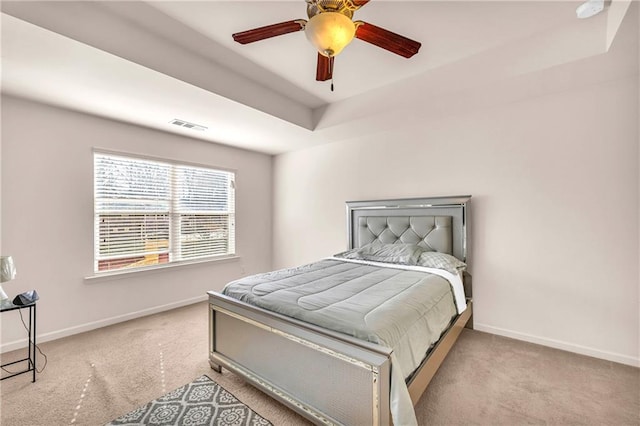 bedroom featuring ceiling fan, light carpet, and a tray ceiling