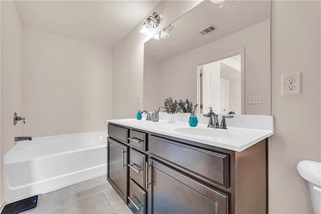 bathroom with a bath, toilet, tile patterned floors, and vanity