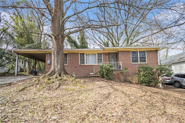 ranch-style house featuring crawl space, driveway, brick siding, and a carport