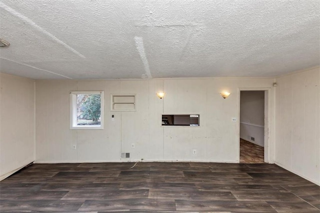 spare room with a textured ceiling, wood finished floors, and visible vents