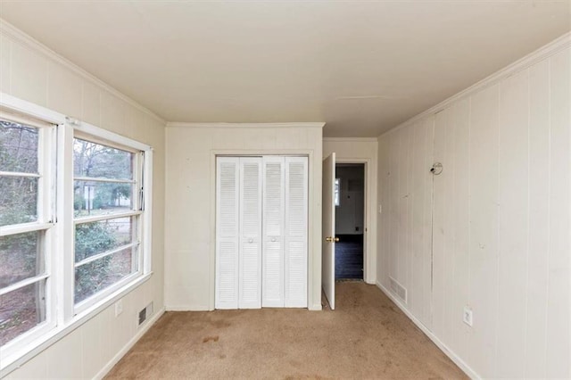 unfurnished bedroom with ornamental molding, light colored carpet, a closet, and visible vents