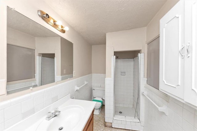 bathroom featuring tile walls, a shower stall, a textured ceiling, and vanity