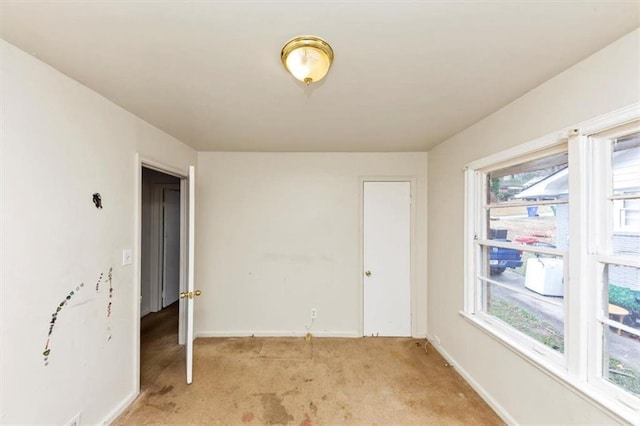 unfurnished room with light colored carpet and baseboards