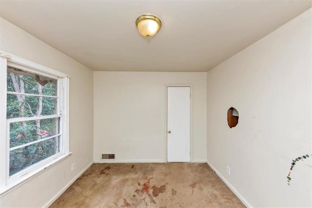 spare room featuring baseboards, visible vents, and light colored carpet