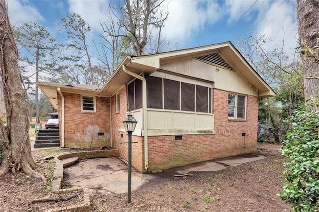 view of property exterior with a sunroom, crawl space, and brick siding