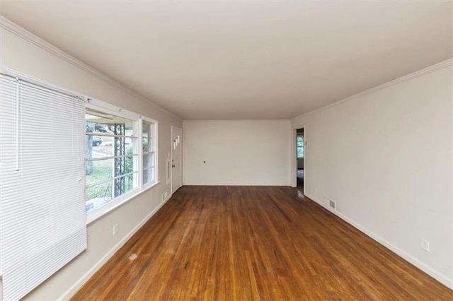 empty room featuring baseboards, visible vents, wood finished floors, and ornamental molding