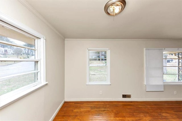 spare room with a wealth of natural light, visible vents, and wood finished floors