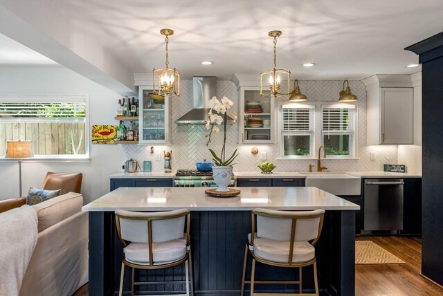 522 Trabert Ave NW, Atlanta, GA 30309 - kitchen with wall chimney range hood, stainless steel dishwasher, light countertops, a chandelier, and a breakfast bar