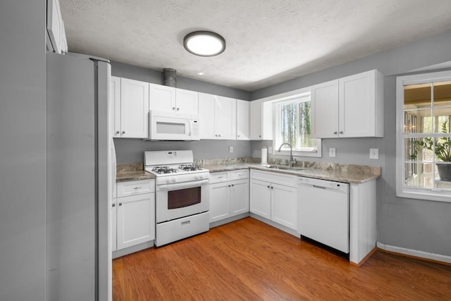 kitchen featuring a sink, white appliances, light wood-style floors, and white cabinets