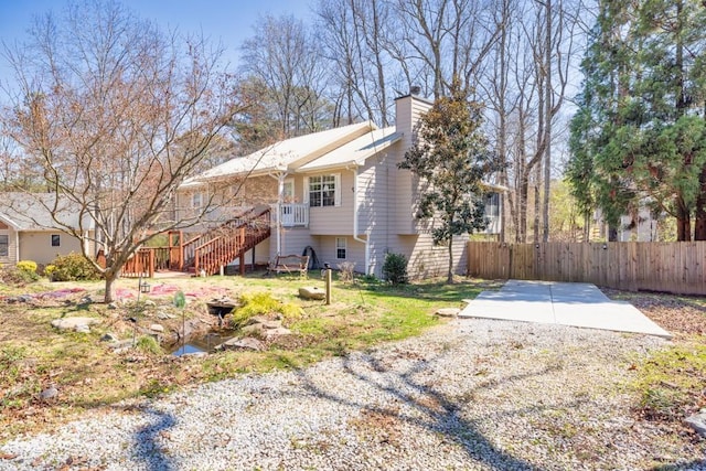 view of side of home featuring stairway, a chimney, and fence