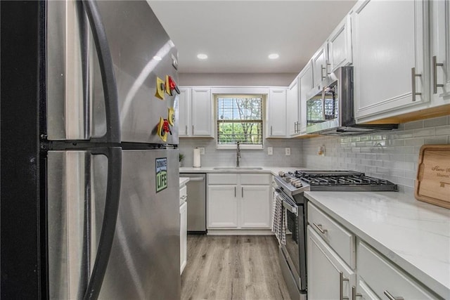 2376 Wellington Cir, Lithonia, GA 30058 - kitchen featuring stainless steel appliances, white cabinets, decorative backsplash, light wood-style flooring, and recessed lighting